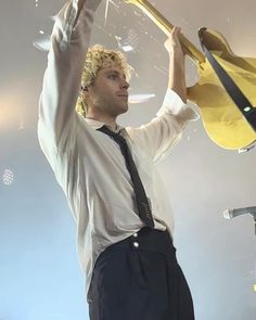 a man in a white shirt and black tie holding up a yellow object with his hands