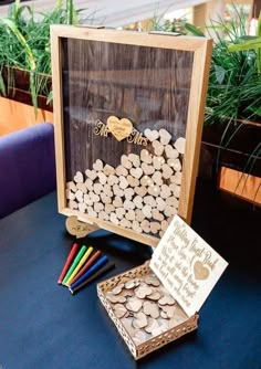 a wooden box filled with lots of wood chips next to a card board and markers