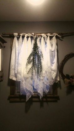 a window with white curtains hanging from it's side in front of a light