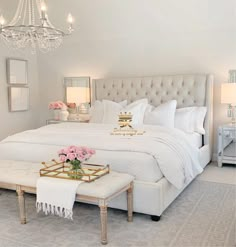 a bed room with a neatly made bed and a chandelier