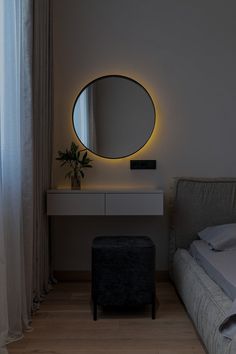 a bedroom with a large round mirror on the wall and a small stool in front of it