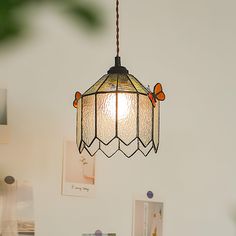 a lamp hanging from the ceiling in a room with pictures on the wall behind it