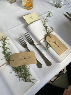 the place setting is set with silverware, napkins, and rosemary sprigs