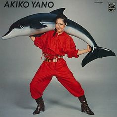 a woman in an orange jumpsuit holding two dolphins