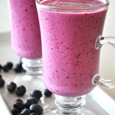 two glasses filled with blueberry smoothie on top of a table