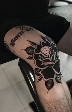 a man with a black rose tattoo on his arm sitting in a barbershop