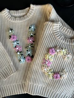 two sweaters with flowers on them are sitting next to each other and one is made out of yarn