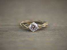 a close up view of a ring with a diamond on the top and bottom, sitting on a wooden surface