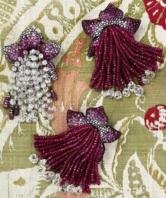 two purple and silver beaded brooches on fabric