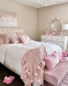 a bedroom decorated in pink and white with a chandelier