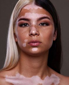 a woman with white hair and makeup is looking at the camera