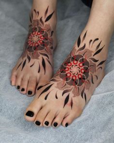 a woman's feet with black and red designs on them, both decorated with flowers