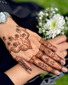 a woman's hand with henna tattoos on it and flowers in the background