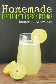 a glass filled with lemonade and limes on top of a wooden table