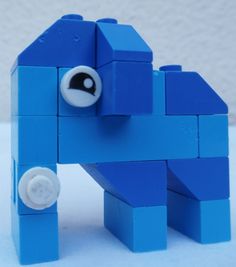 a blue toy horse made out of legos on a white surface with a wall in the background