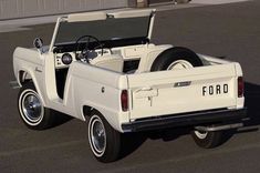 an old ford pickup truck parked in a parking lot with the hood open and it's flatbed