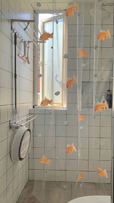 a bathroom with goldfish in the shower and on the wall, there is a toilet