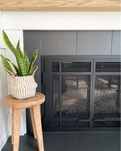 a potted plant sitting on top of a wooden stool next to a fire place