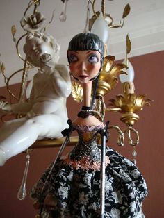 a figurine is posed next to a chandelier