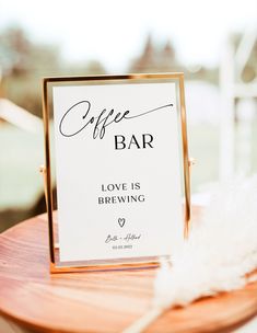 an open bar sign sitting on top of a wooden table next to a white feather