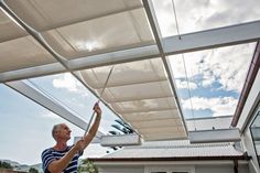 a man standing under a white awning on top of a roof next to a building