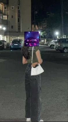 a woman standing in the middle of a parking lot with her laptop on her head