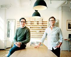 two men sitting at a table in an office