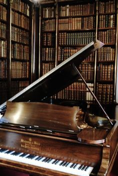 a grand piano in front of a bookshelf