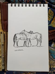 two horses standing next to each other on a piece of paper in front of a purse