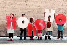 children holding up letters that spell out the word hope in front of a brick wall