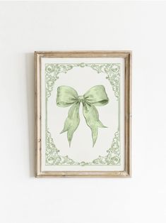 a green bow is hanging on the wall above a framed painting with an ornate frame