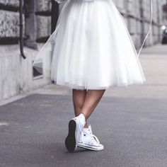 a woman is walking down the street in a white dress