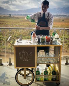 a man standing behind a cart filled with drinks