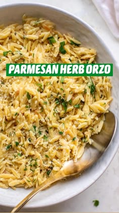 a bowl filled with pasta and parsley on top of a white tablecloth next to a silver spoon