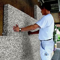 a man standing next to a wall with his hand on it