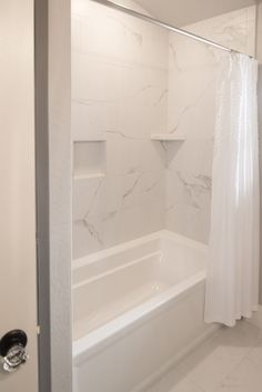 a white bath tub sitting next to a shower