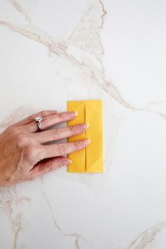 a person's hand on top of a yellow piece of paper