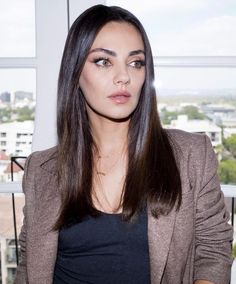 a woman with long hair standing in front of a window