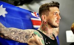 a man with tattoos on his arm and chest holding an australian flag in front of him