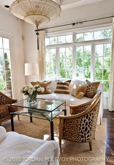 a living room with couches, chairs and a table in front of two windows