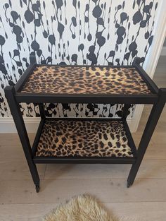 a leopard print side table with two shelves on each side and a rug in front of it