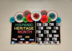 a bulletin board with flowers and pictures on it in front of a white brick wall