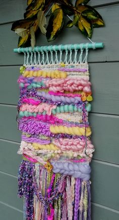 a wall hanging made out of different colored yarns and beads on a green hook