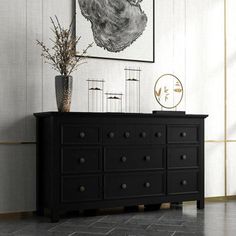 a black dresser sitting in front of a painting on the wall