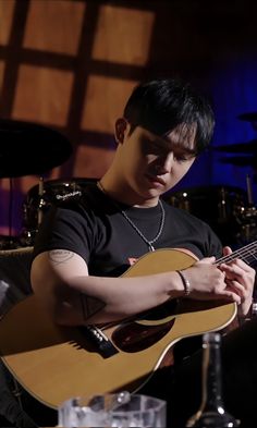 a young man is playing an acoustic guitar