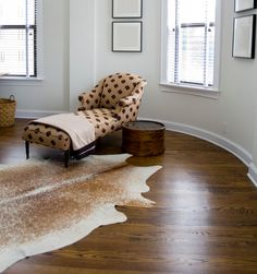 a chair sitting on top of a hard wood floor next to two windows in a living room