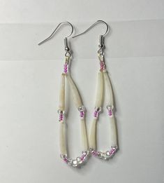 pair of white and pink beads hanging from silver earwires on top of table