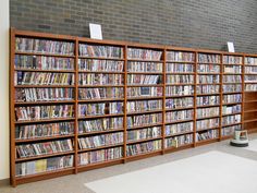 several bookshelves filled with many different types of dvd's in a library