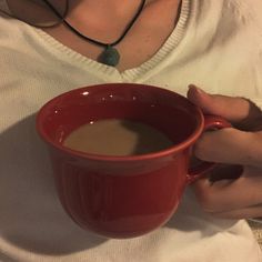 a woman is holding a red coffee cup