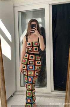 a woman taking a selfie in front of a mirror wearing a colorful crochet dress